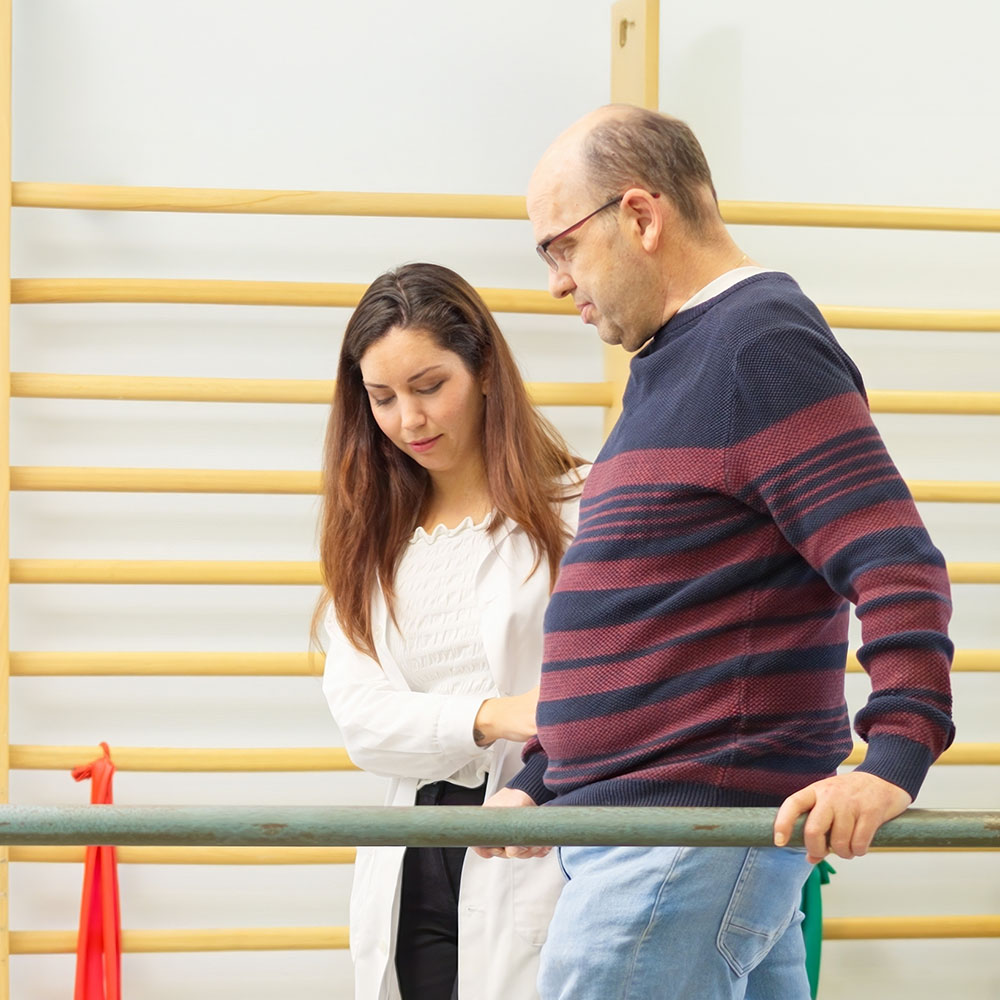 Elderly man assisted by young woman while receiving physical therapy